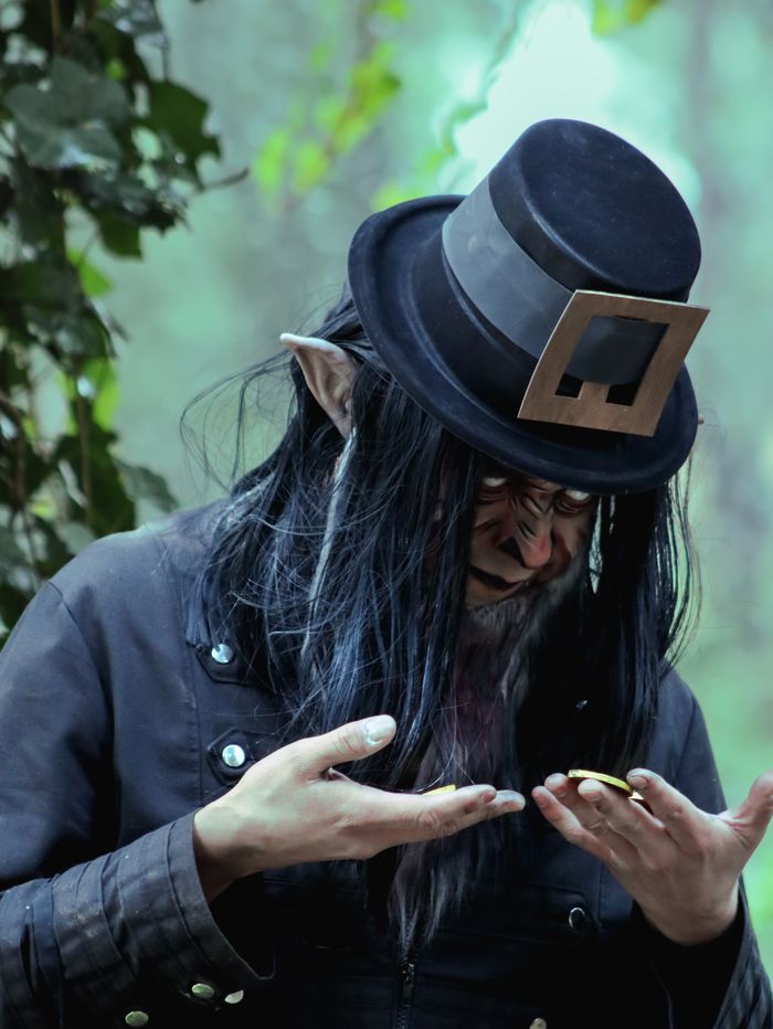 Anasayfa A mysterious elf character examines a gold coin in a forest setting, blending fantasy and intrigue.